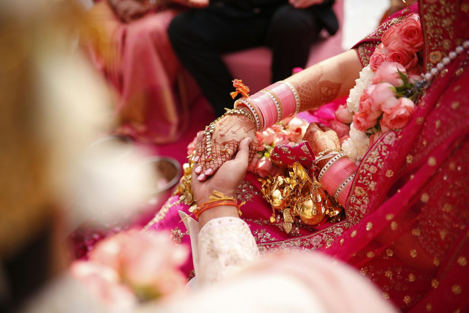 About Close-up of hands exchanging vows during a vibrant Indian wedding ceremony with floral and jewelry accents.